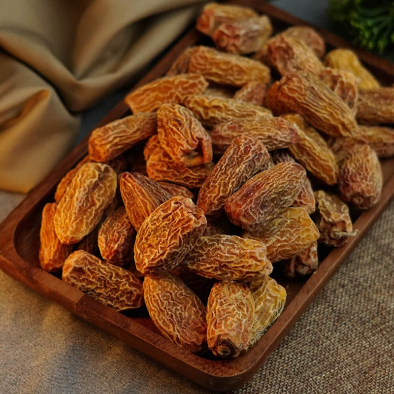 A bowl of fresh, golden Yellow Dry Dates on a wooden table.