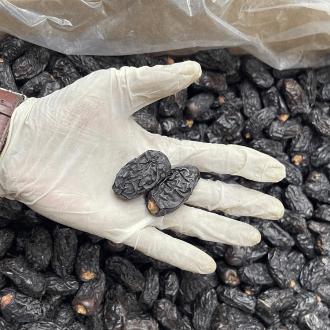 "Close-up of Qalmi Dates showcasing their deep brown color and wrinkled texture"